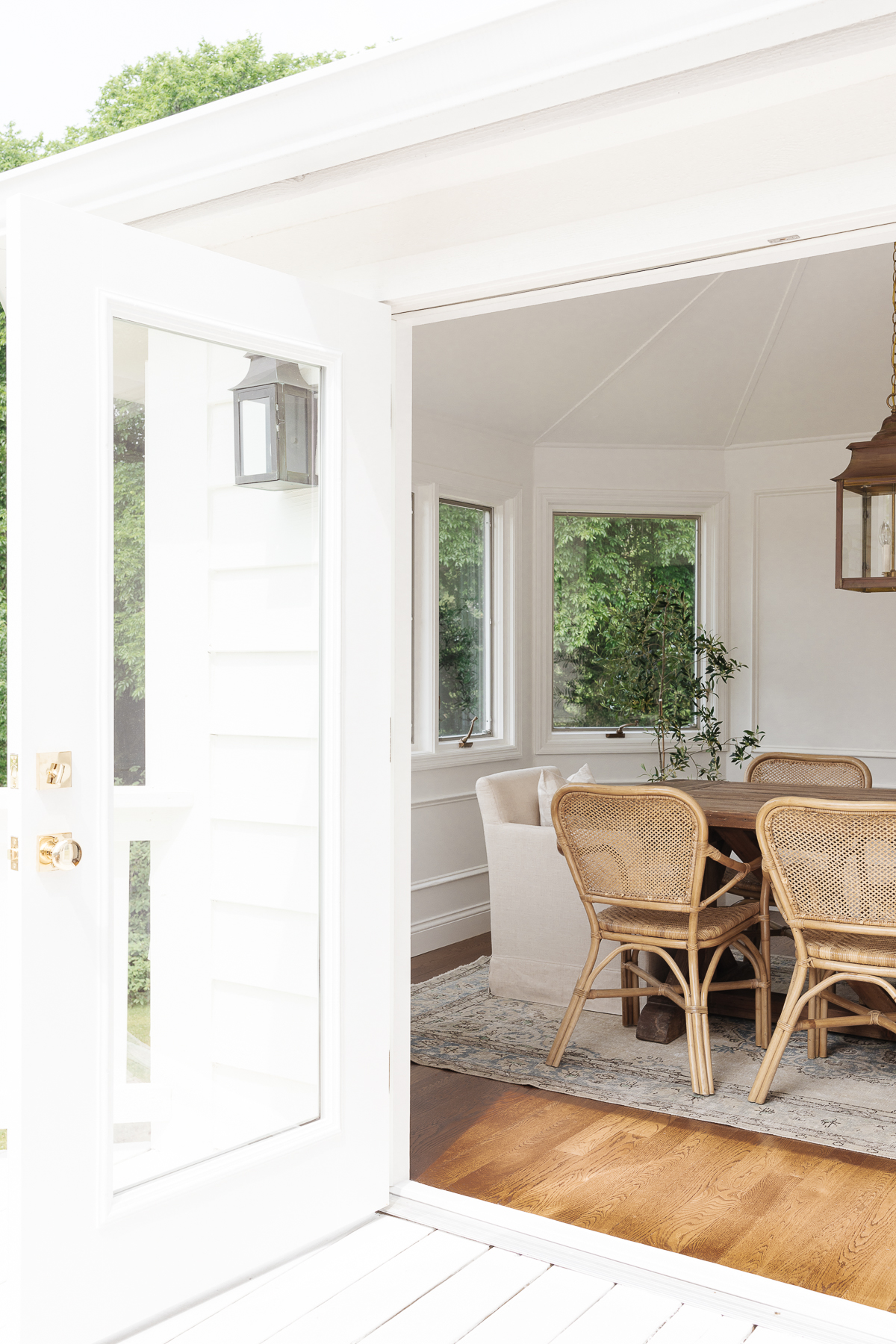 Open doors into a dining room leading out to a white painted deck. 