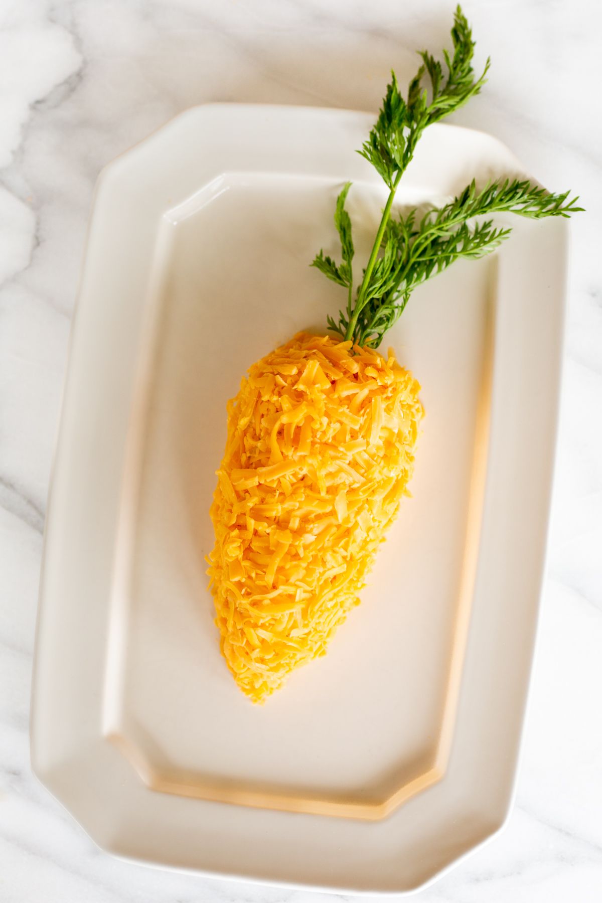A carrot cheese ball on a white platter.