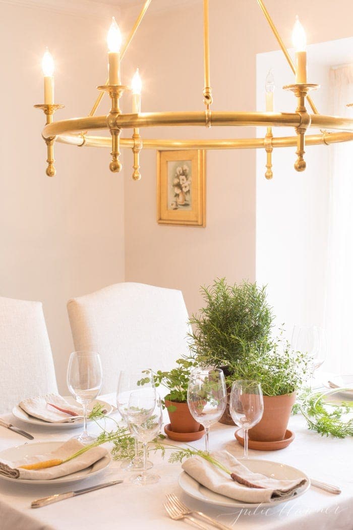 An Easter table set with herbs and a fresh carrot at each place setting