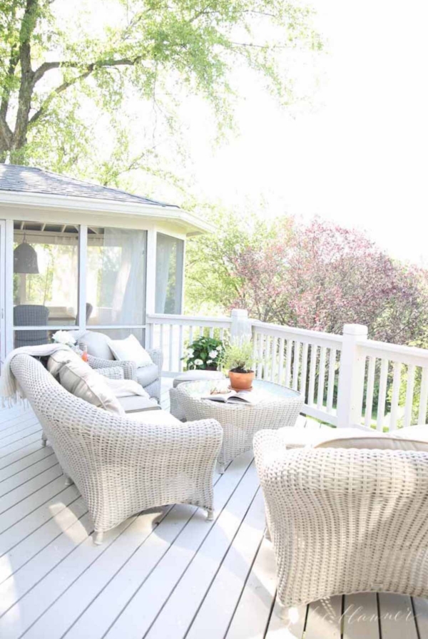 A white painted deck featuring white wicker furniture.