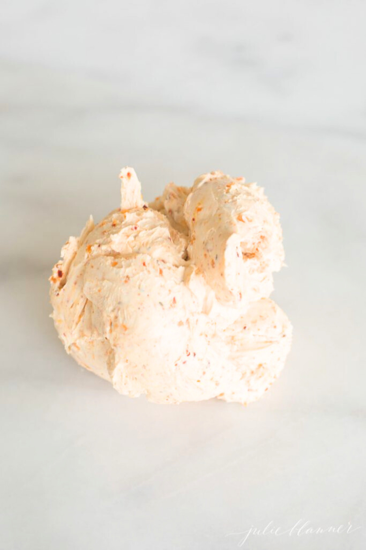 A spicy cheese ball on a marble countertop. 