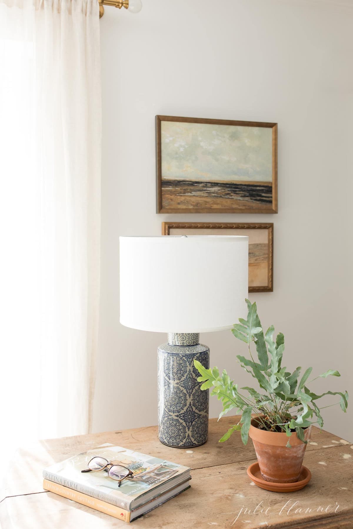 A white living room with a soft wood table, blue lamp and a low maintenance indoor plant