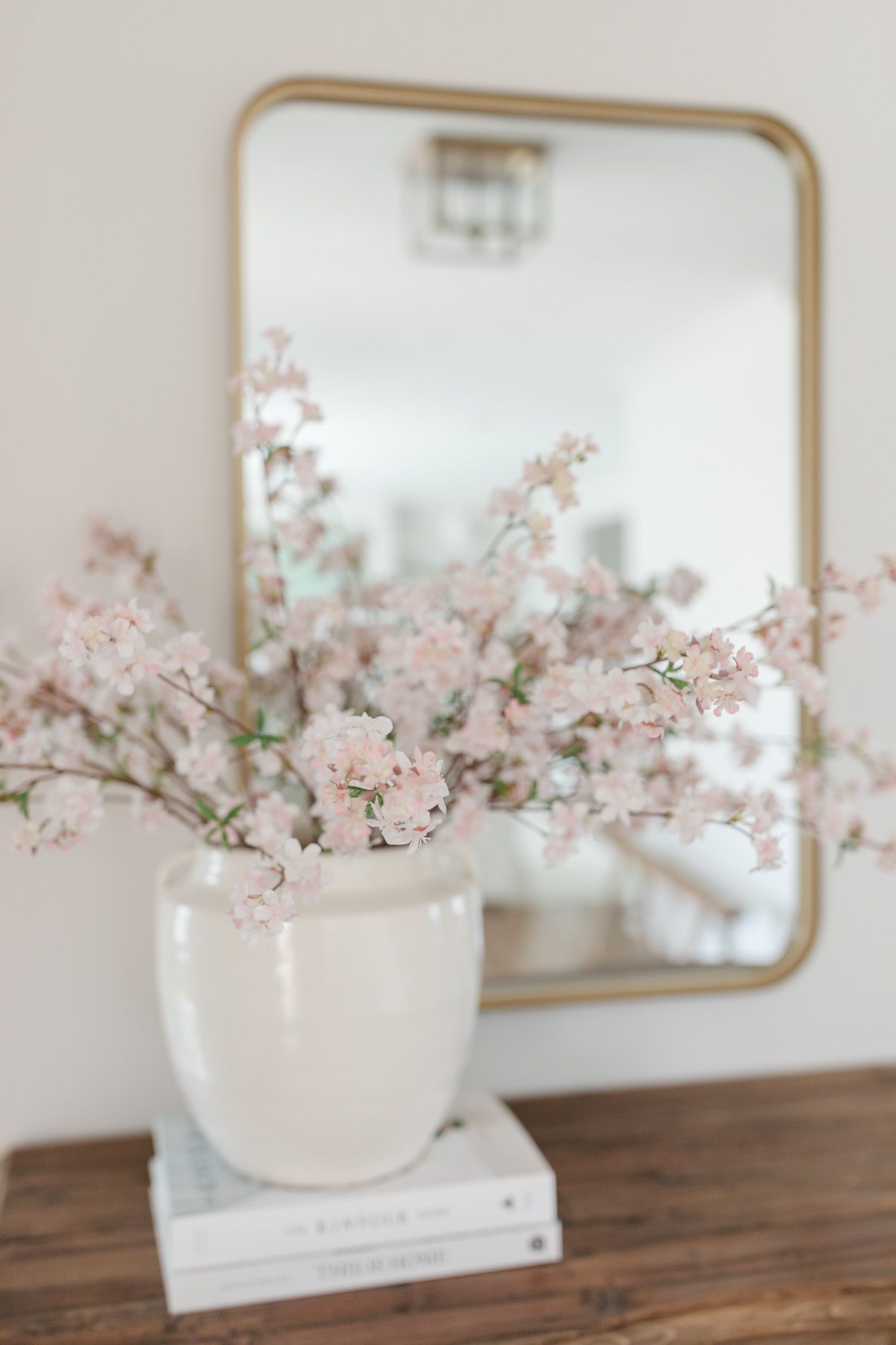 Fake flowers in a white vase in front of a yellow mirror