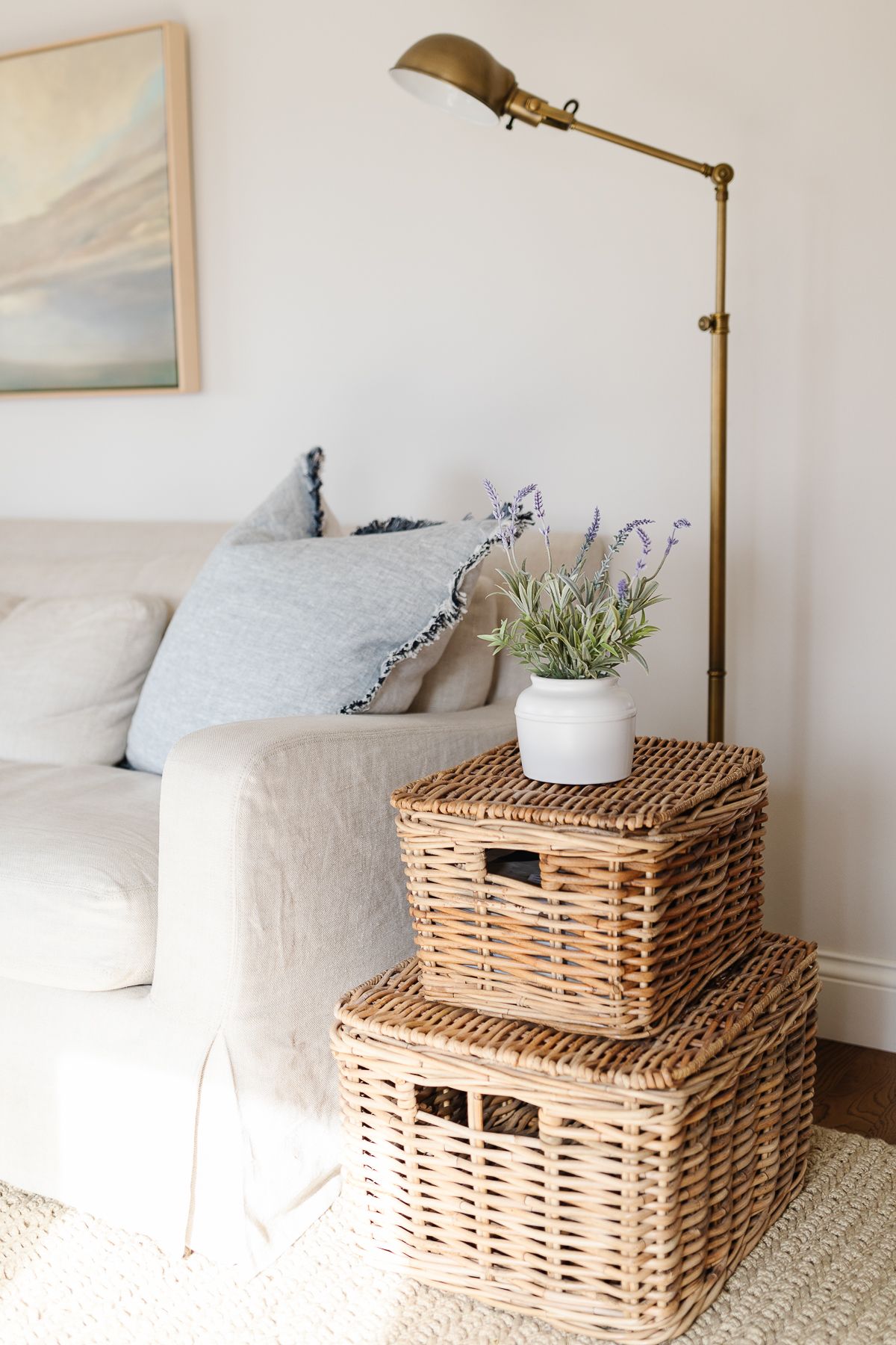 A living room with faux potted lavender on a stack of baskets