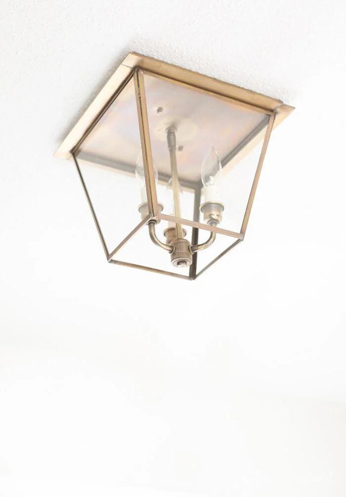 An antique brass flush mount lantern on a white ceiling. 