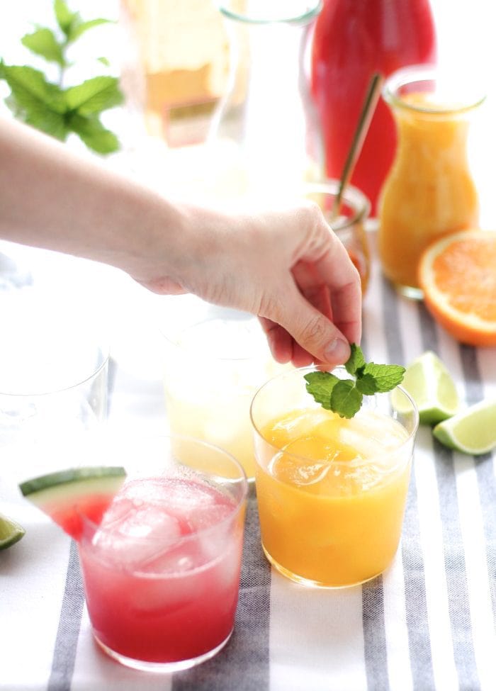 A hand placing a garnish on a mango margarita