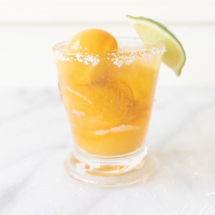 A margarita float made with mango sorbet, garnished with lime, on a white marble surface