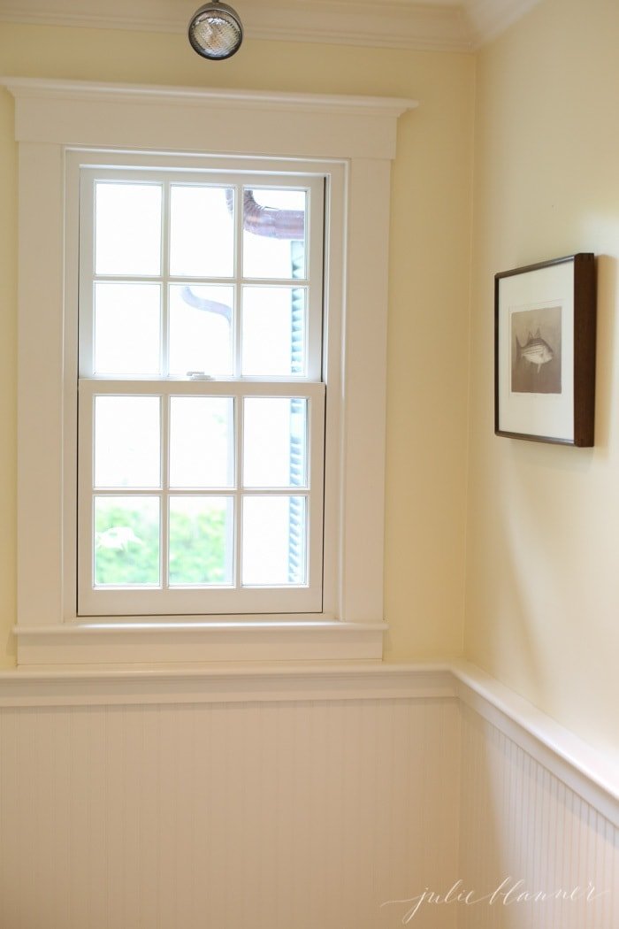 A simple Hob Knob hotel room in martha's vineyard with white beadboard and a window.