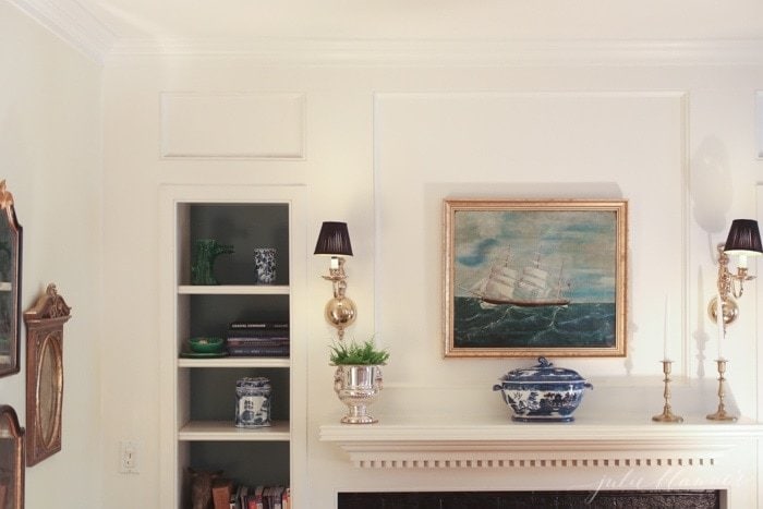 A traditional colonial inspired fireplace and built-ins with wall sconces.