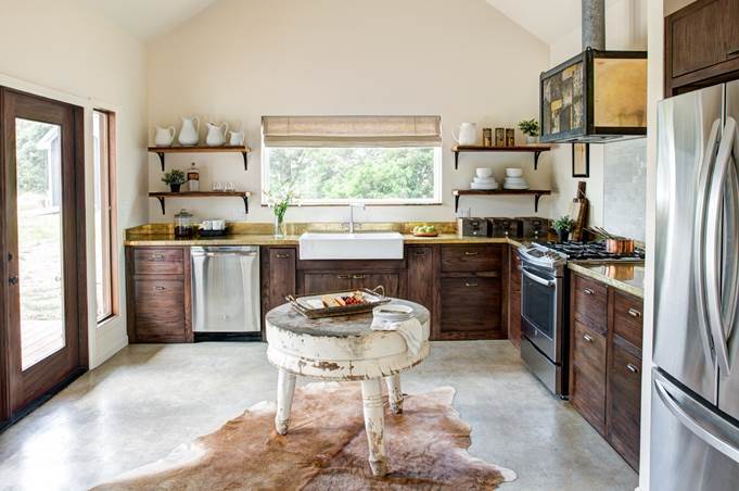 Rustic wood farmhouse kitchen with brass counter tops and a round butcher block island in the center.