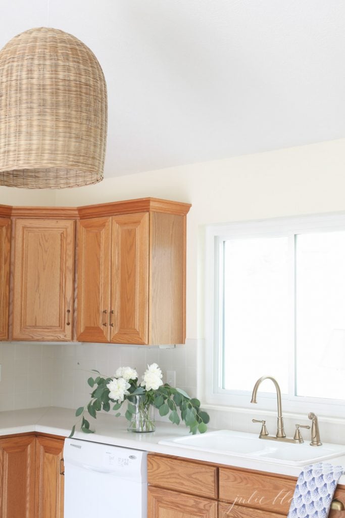 Large rattan pendant adds warm color and texture to a kitchen with oak cabinets.