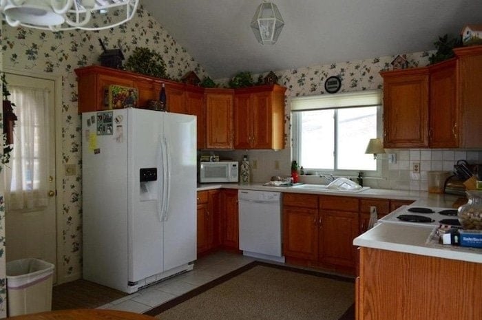 Lake cottage kitchen before. Kitchen with oak cabinets and floral wallpaper.