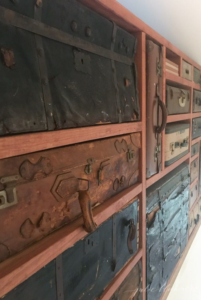 A vintage suitcase display case between wooden beams.