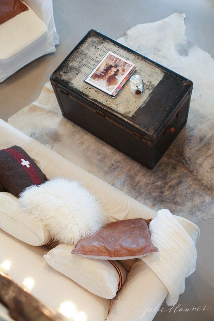 Farmhouse Interior Design styled living room featuring white sofas and a vintage trunk coffee table.