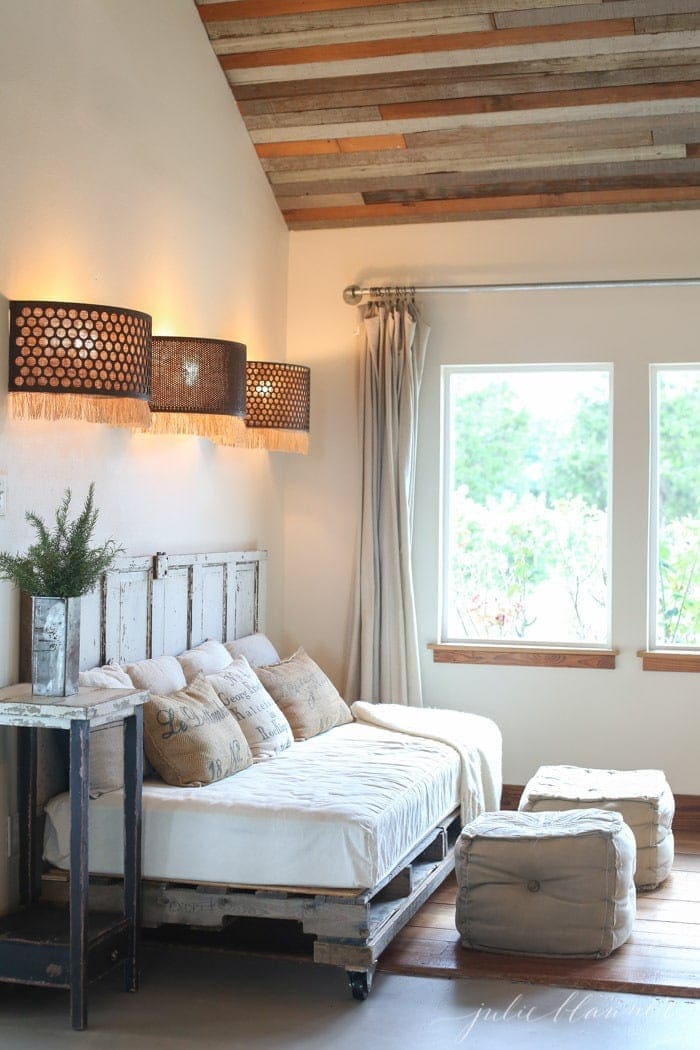 Three light fixtures in an industrial farmhouse with a pallet daybed.
