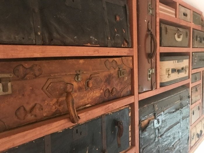 A vintage suitcase display case between wooden beams.