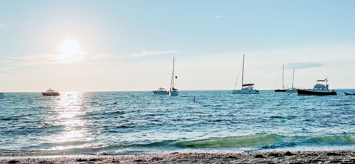 A Martha's Vineyard beach and ocean scene, with sailboats throughout