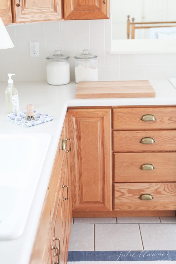 Making a dated kitchen feel modern is easy with new cabinet hardware. Oak cabinets look beautiful with warm brass cabinet pulls and cup pulls.