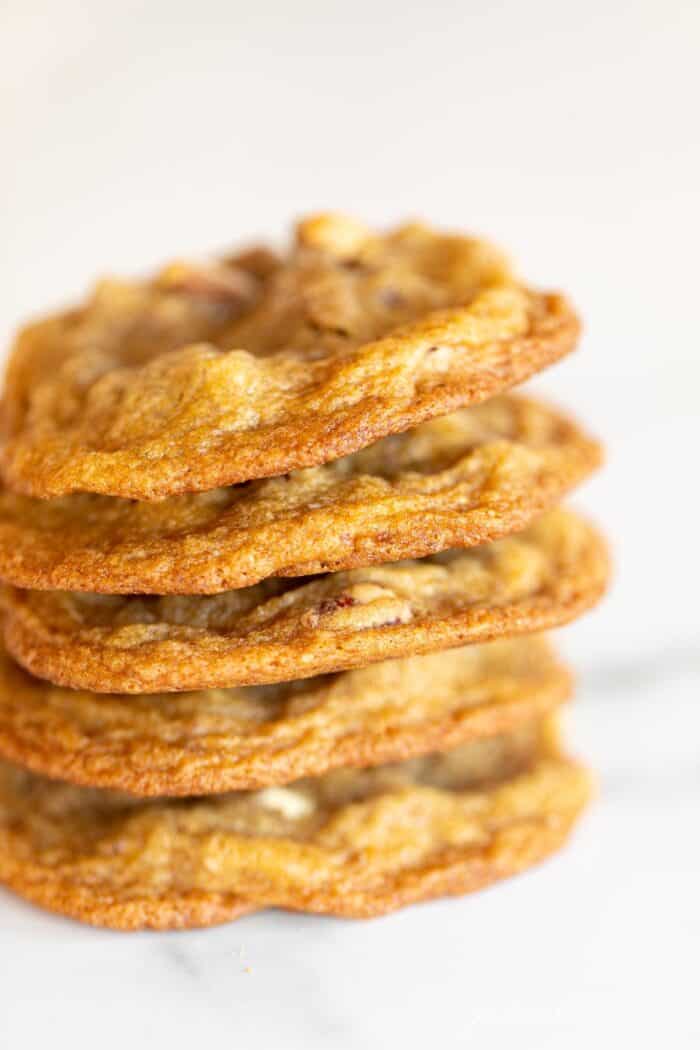 A stack of thin pecan pie cookies on a marble surface.