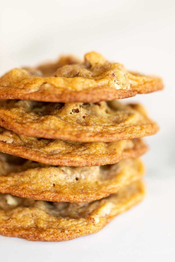 A stack of thin pecan pie cookies on a marble surface.