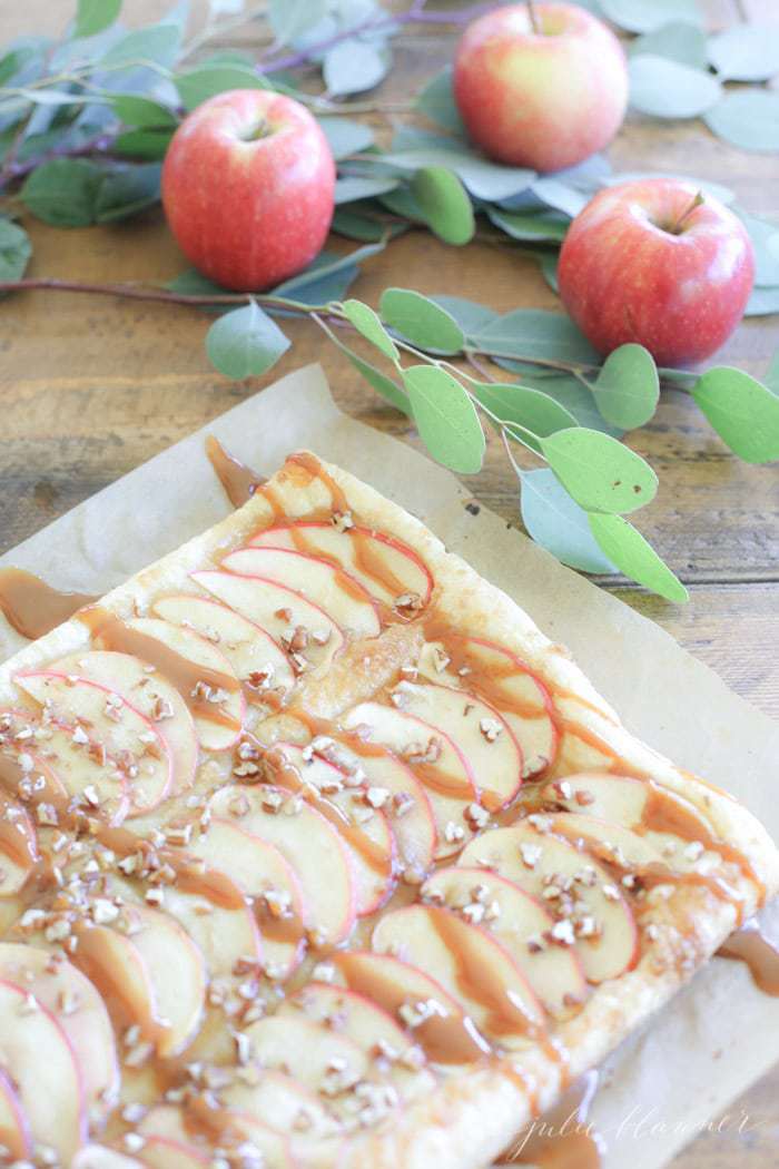 A caramel apple tart topped with chopped nuts.