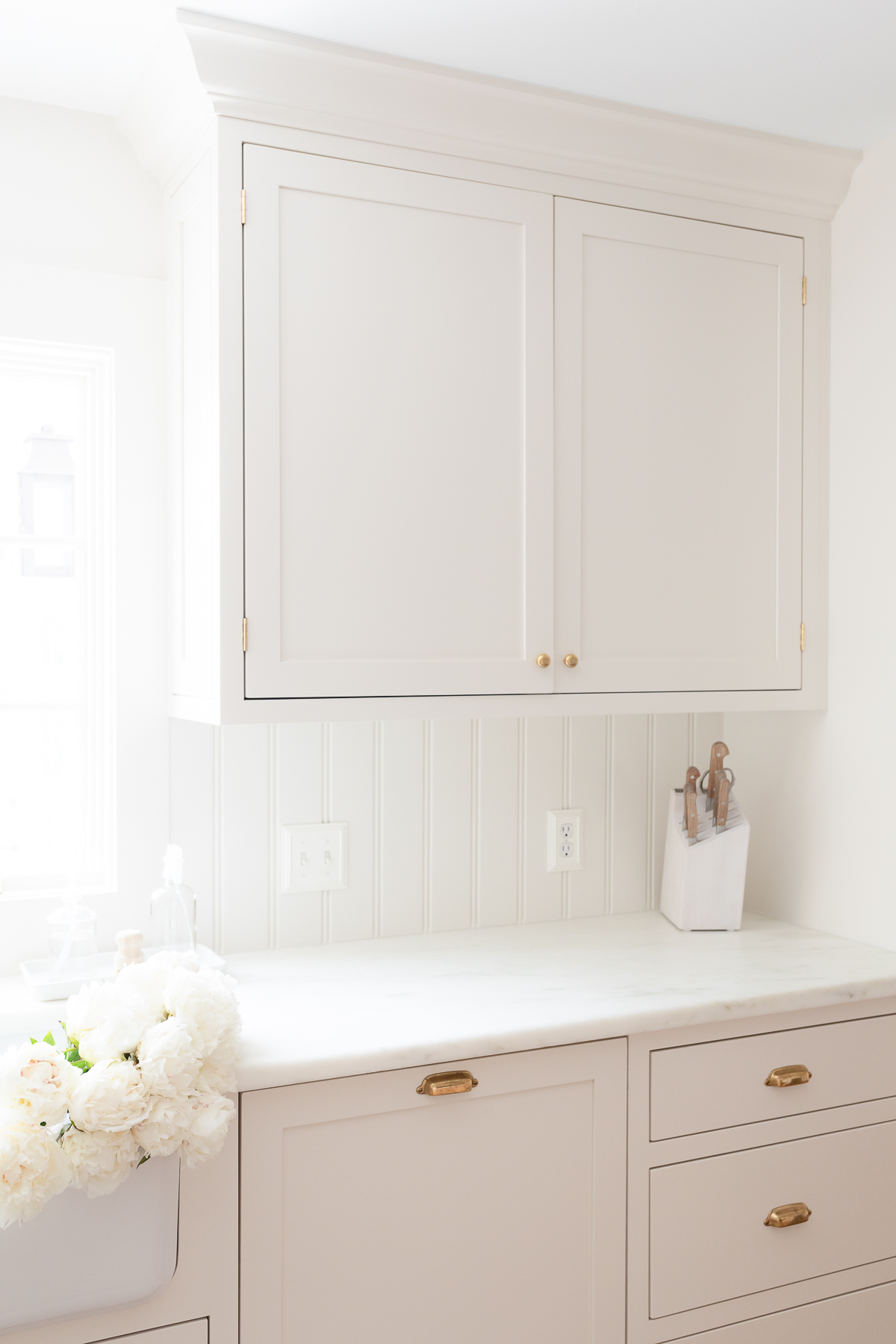 Cream kitchen cabinet with brass knobs in a traditional kitchen.