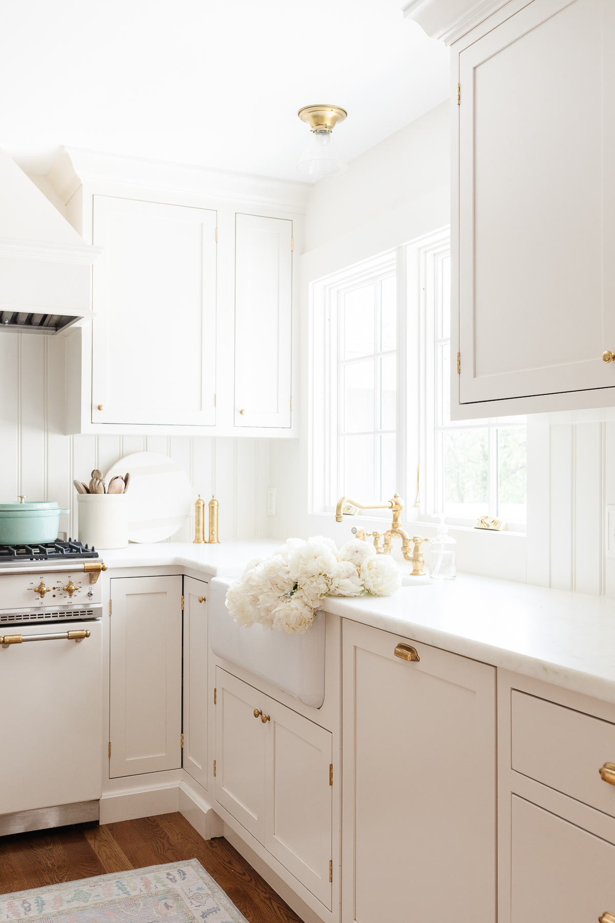 Cream kitchen cabinet with brass knobs in a traditional kitchen.