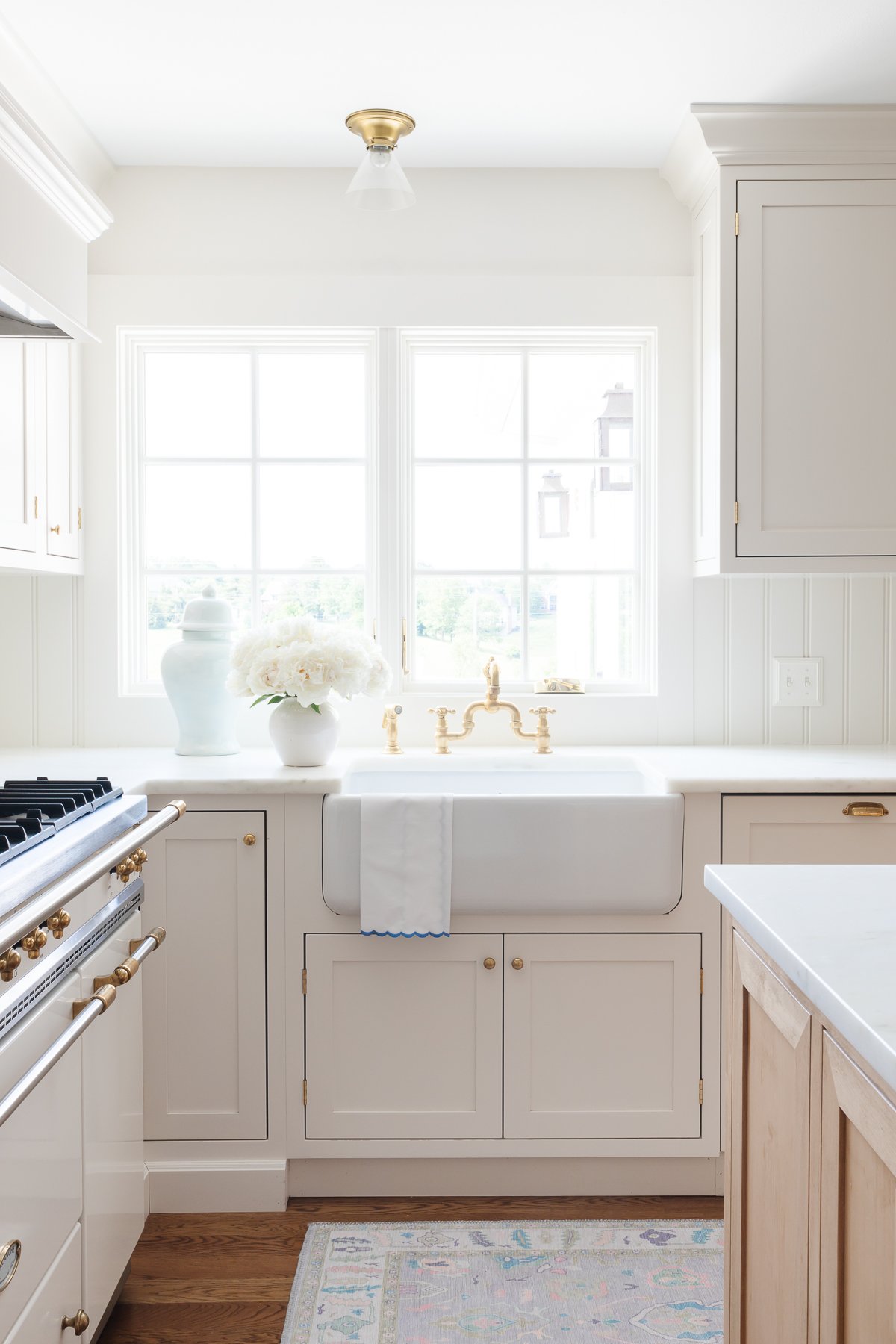 Cream kitchen cabinet with brass knobs in a traditional kitchen.