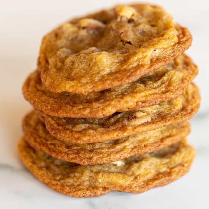 A stack of thin pecan pie cookies on a marble surface.