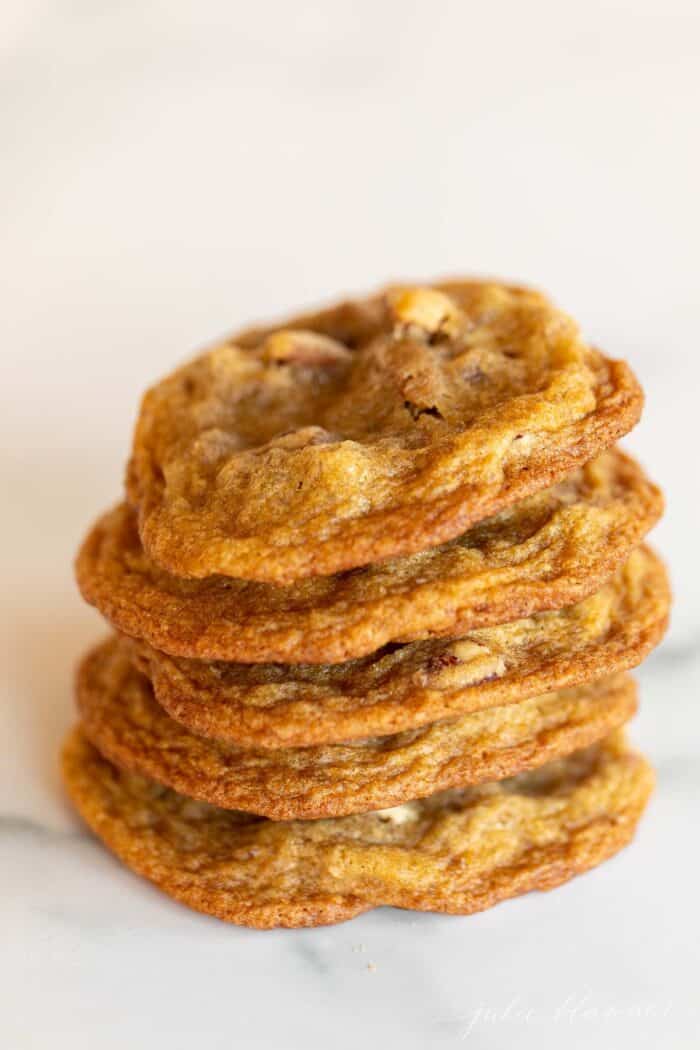 A stack of thin pecan pie cookies on a marble surface.