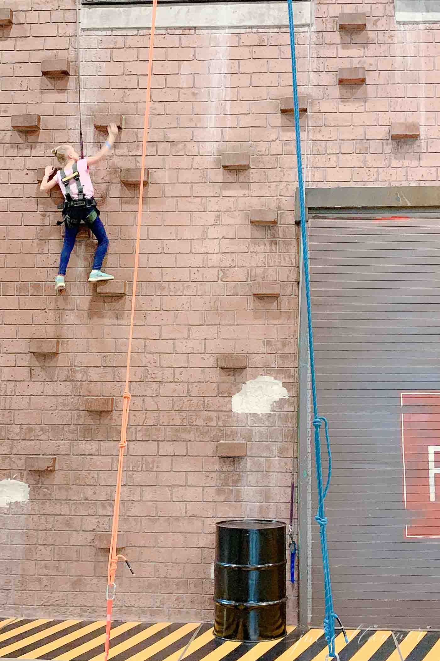 A little girl climbing a wall at the Branson attraction, Fritzs