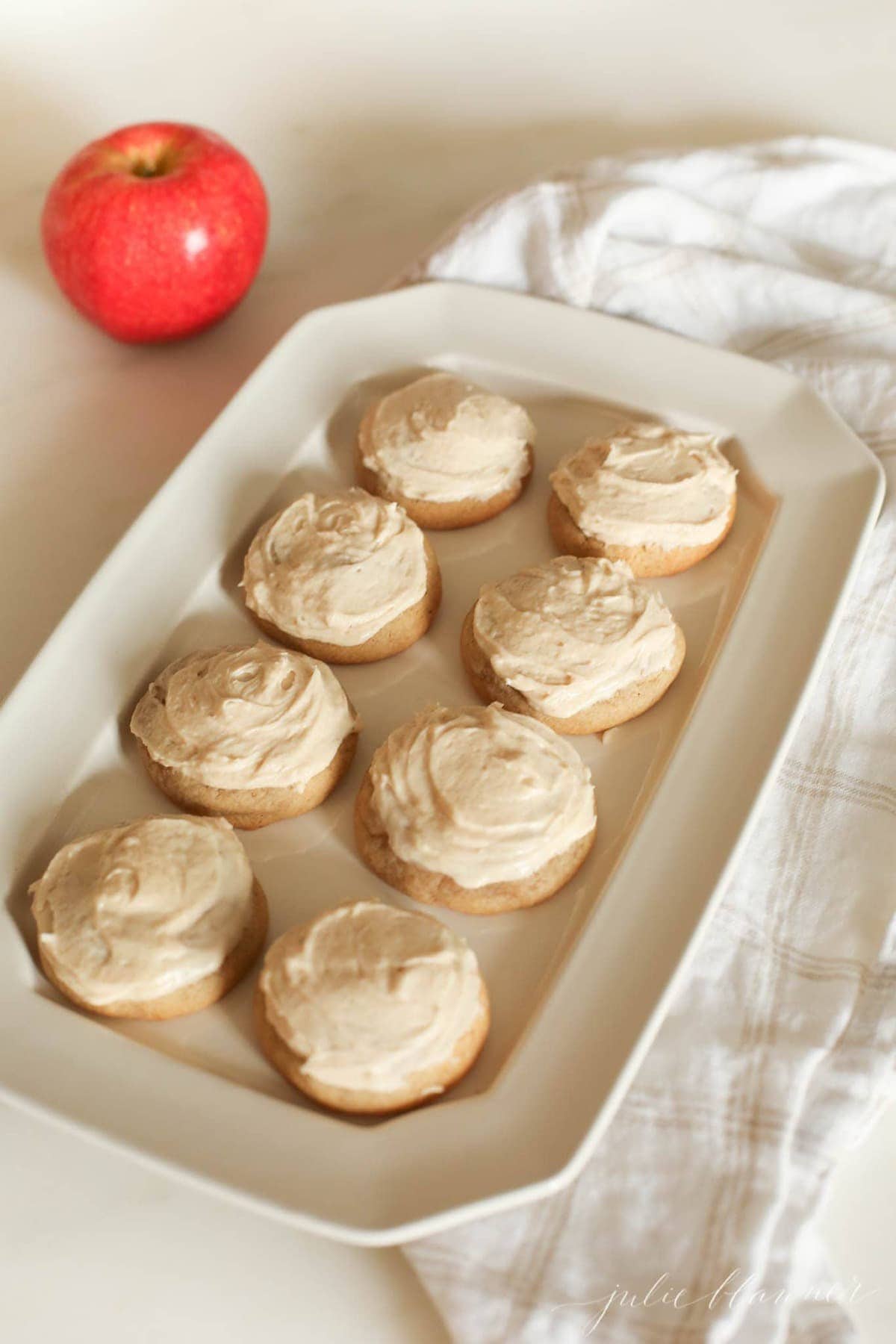 Eight cookies with frosting on a white plate