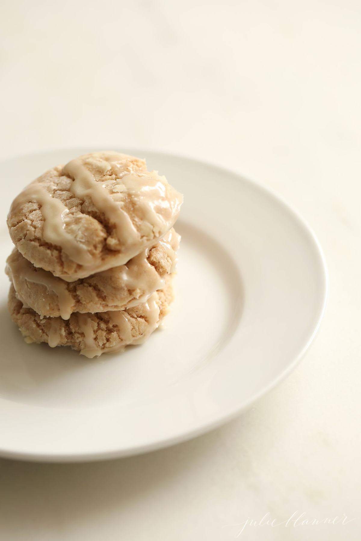 glazed apple pie spice cookies stacked on a white plate
