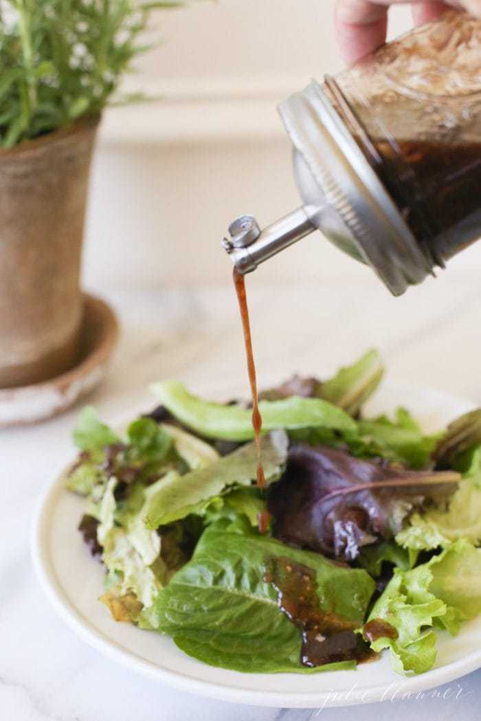 balsamic vinaigrette being poured onto a bed of lettuce