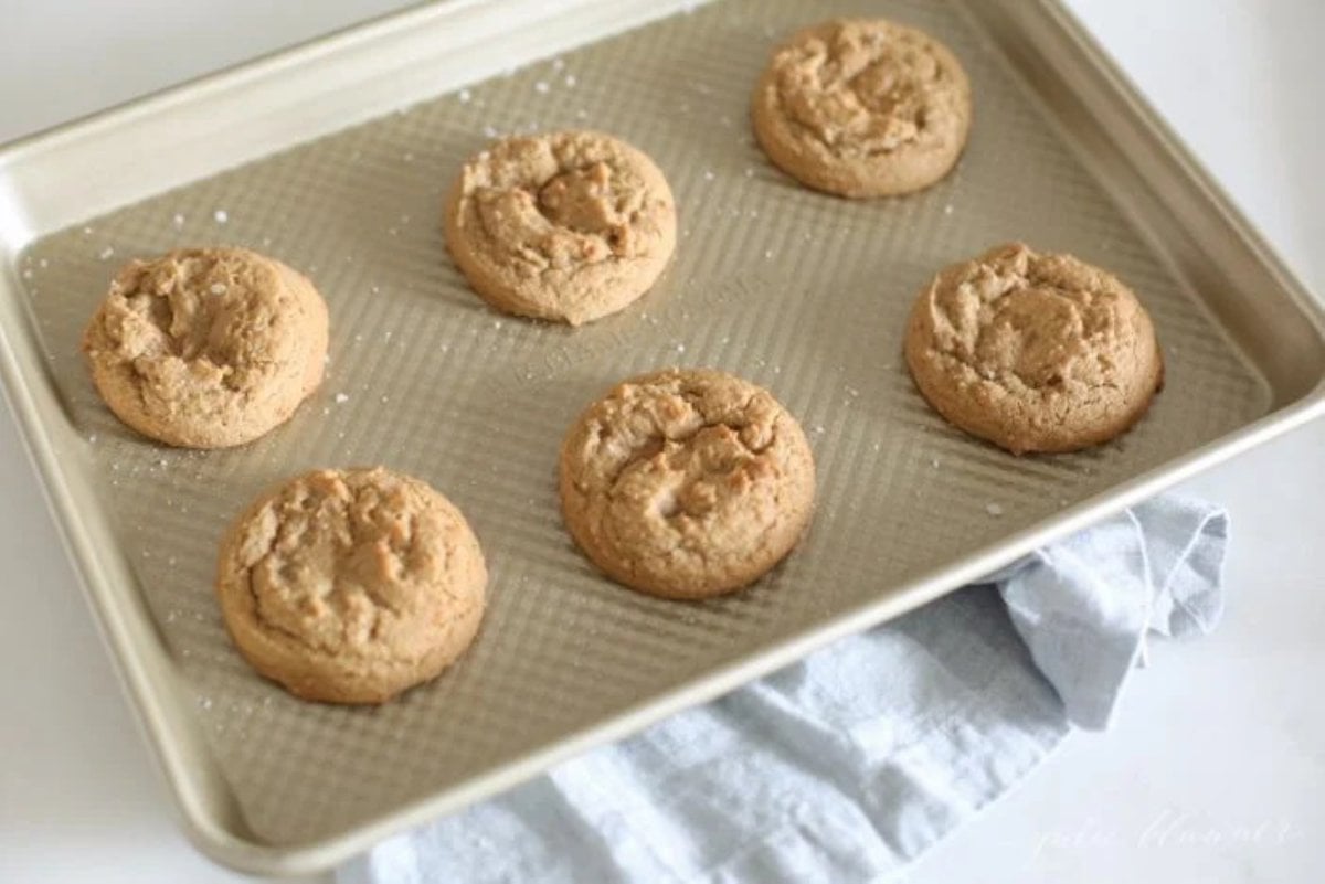 Brown sugar cookies on a gold baking sheet after coming out of the oven.