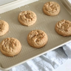Brown sugar cookies on a gold baking sheet after coming out of the oven.