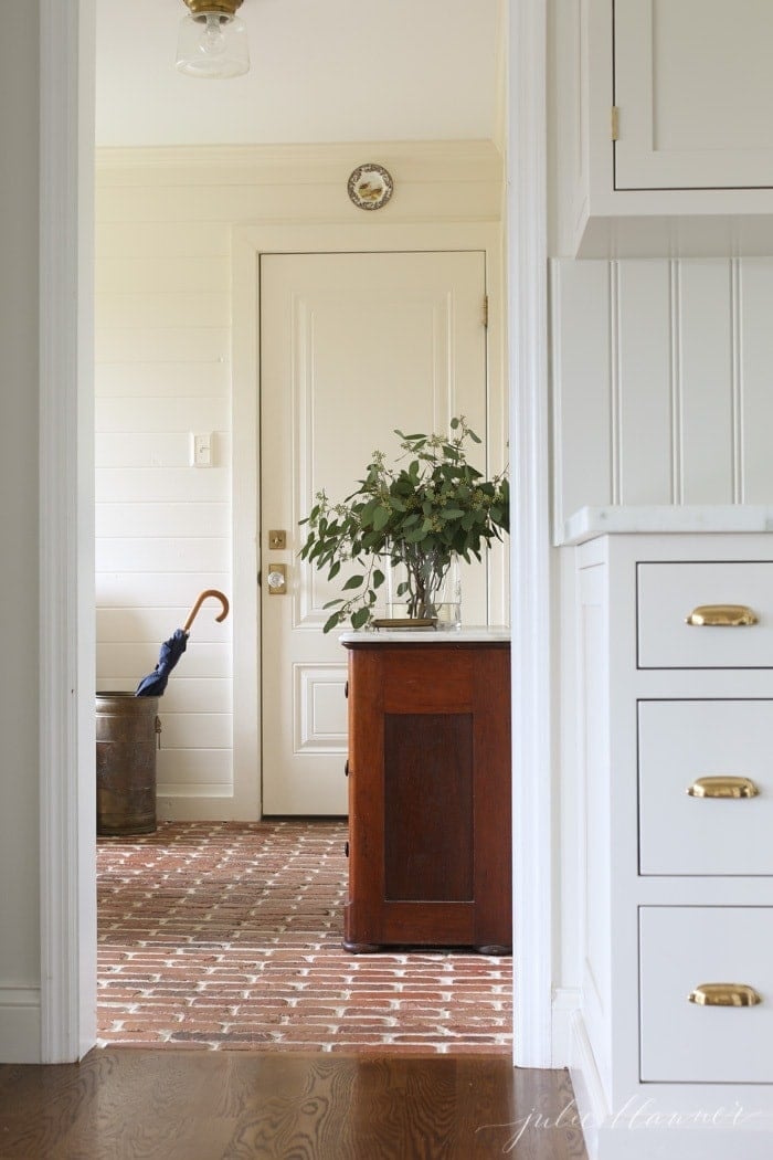 mudroom with brick floor and cream shiplap walls decorated for fall
