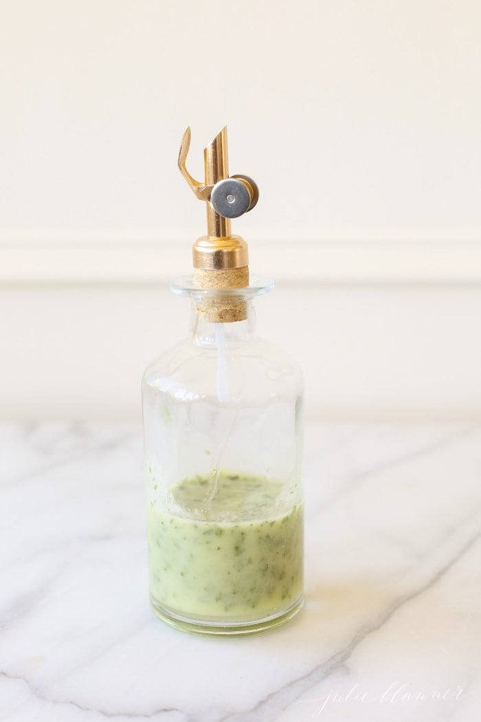 Herb vinaigrette in a clear class bottle with a gold spout. 