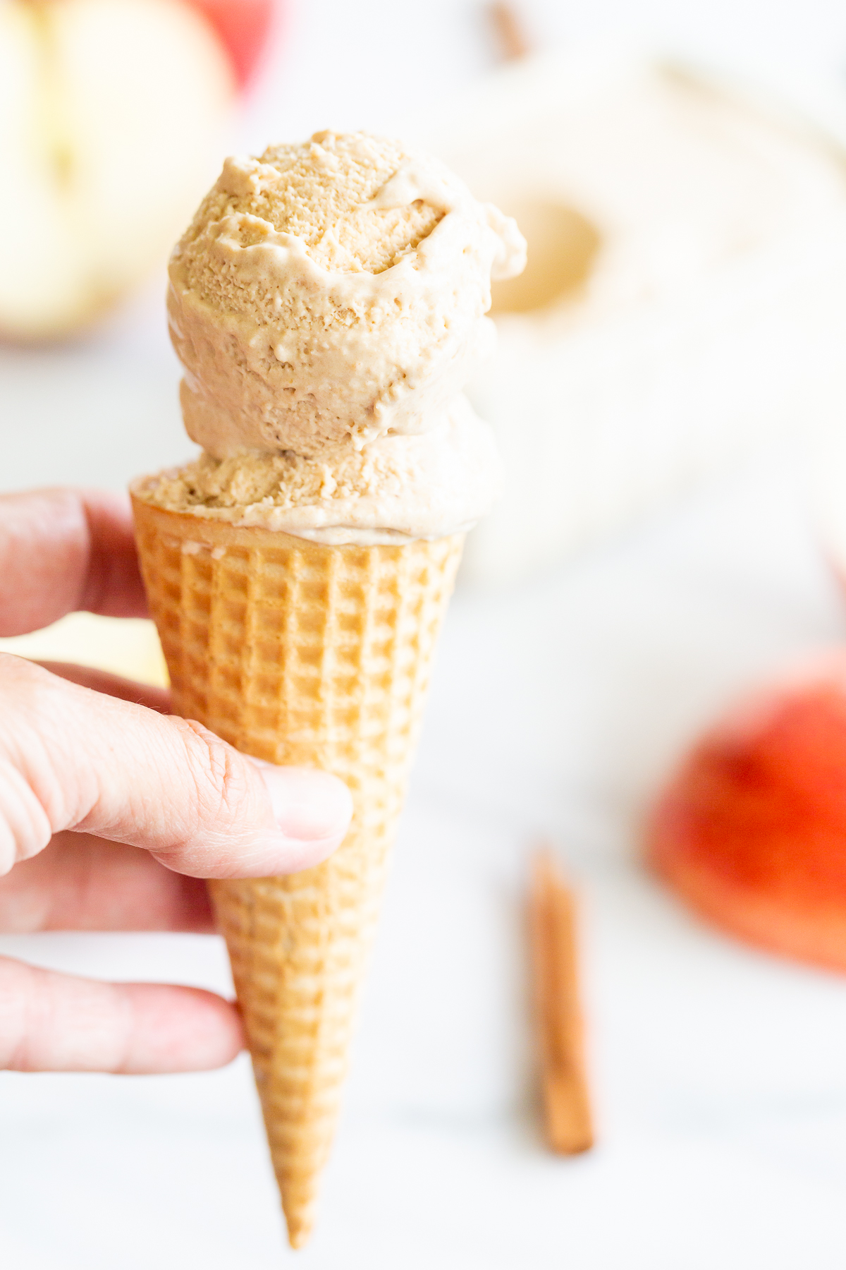 A hand holding an apple ice cream cone