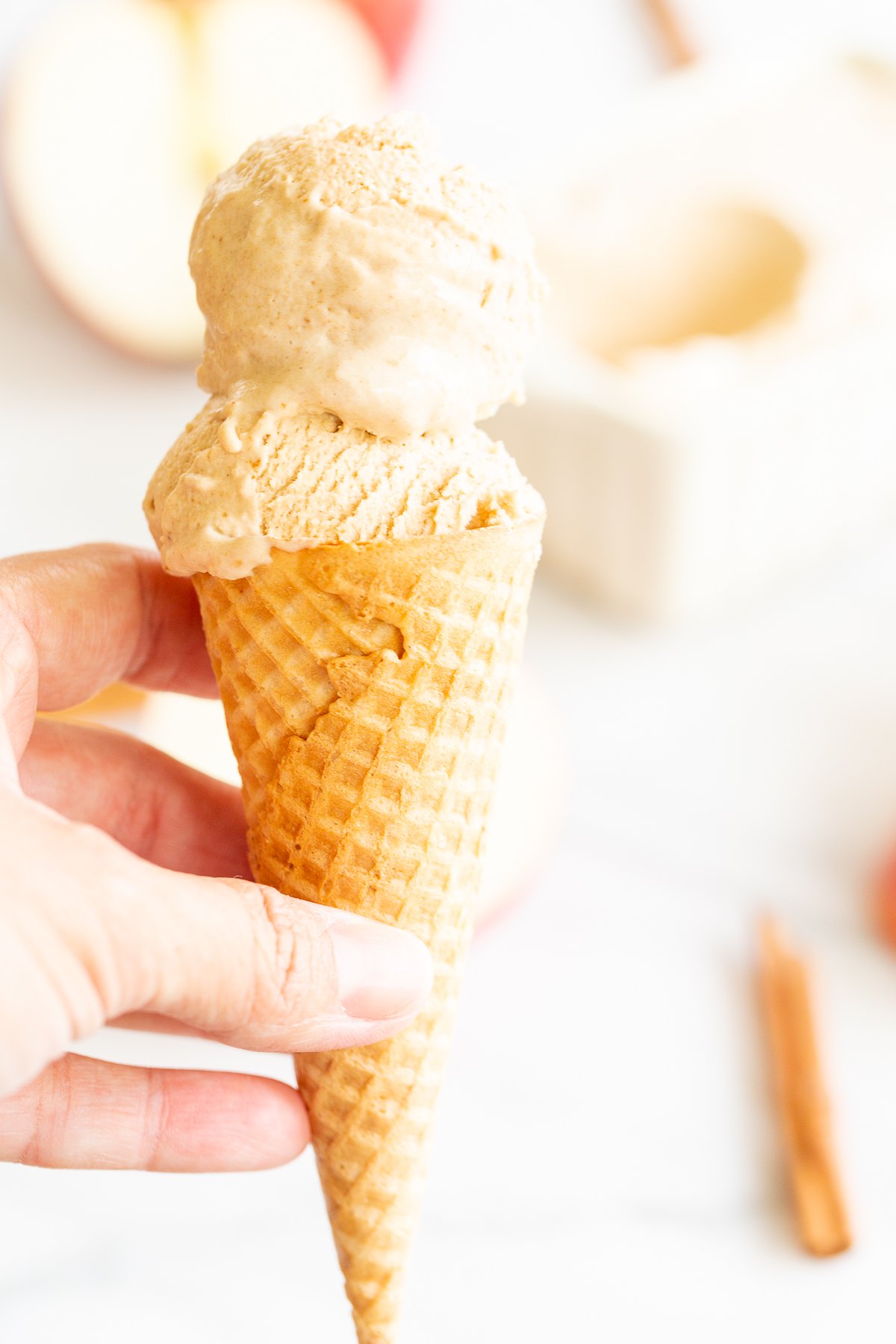 A hand holding an apple ice cream cone 