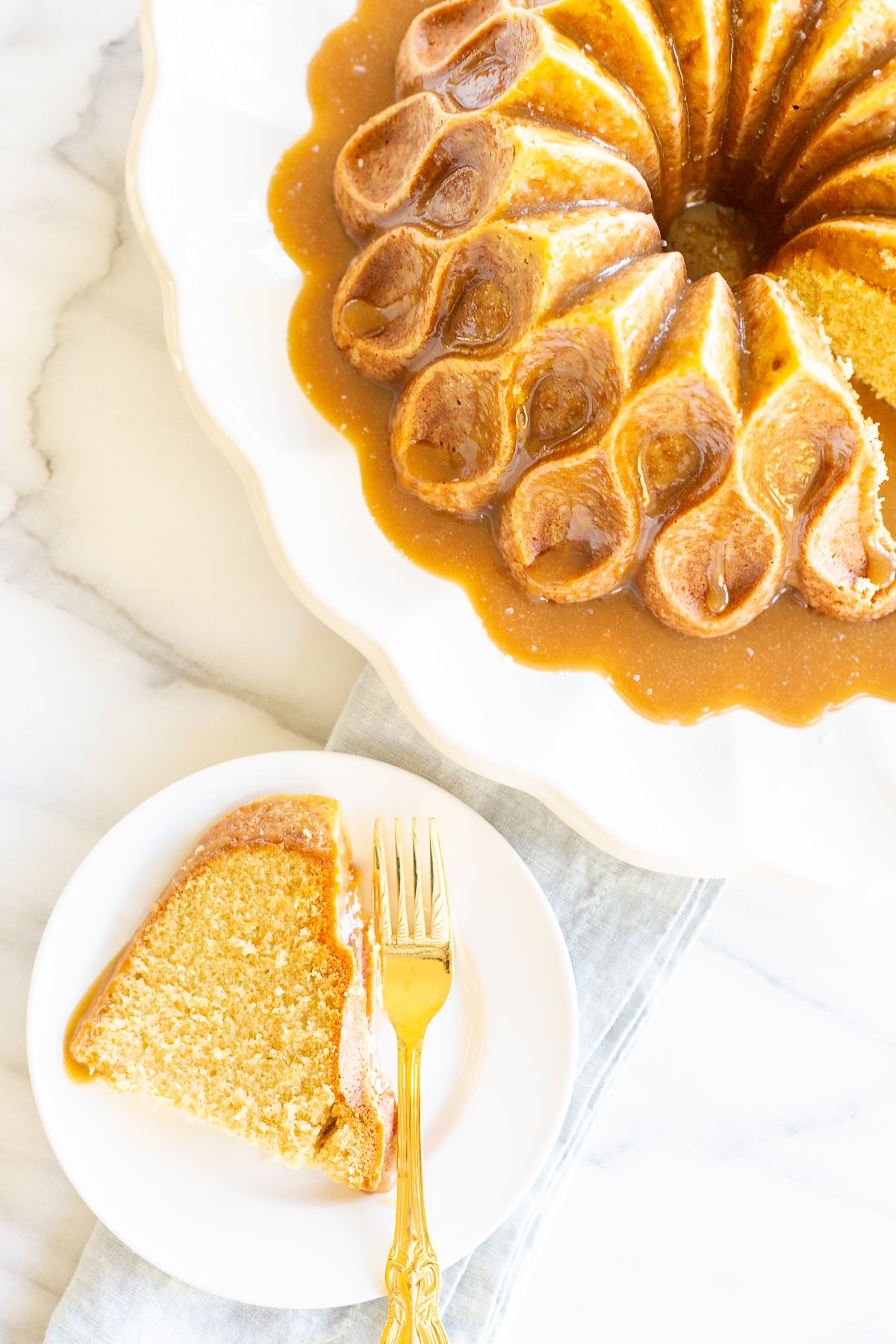 A slice of brown sugar caramel pound cake on a white plate, with the bundt cake in the background.
