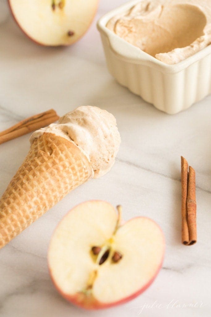 creamy apple butter ice cream in a waffle cone with a loaf pan in the background.