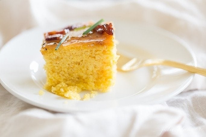 homemade cornbread with maple butter on white plate with gold fork