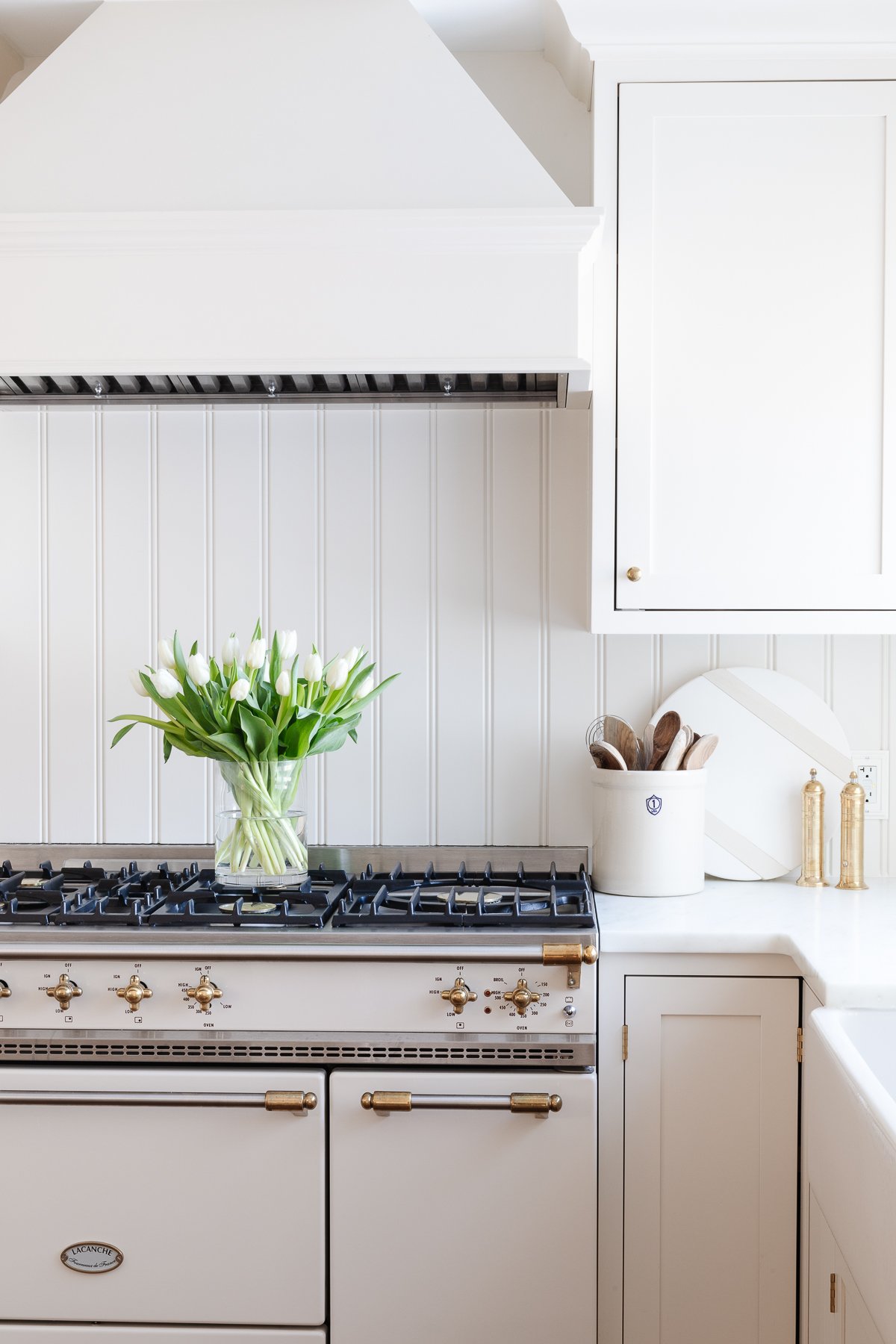 A white kitchen with a white stove and beadboard backsplash.