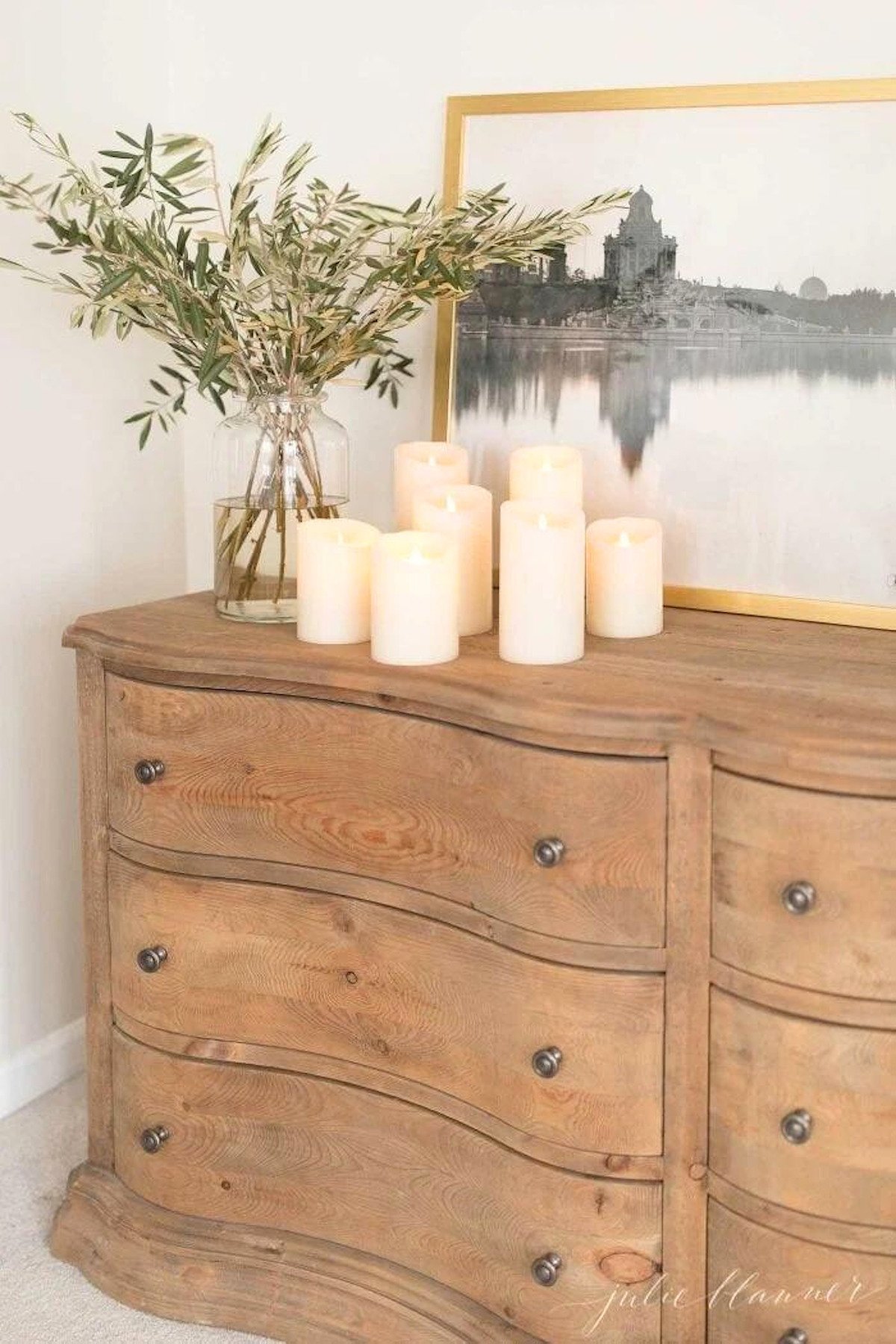 A wooden dresser with candles and Christmas lights.