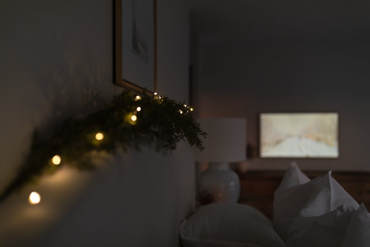 A cozy bed in a room adorned with twinkling Christmas lights.