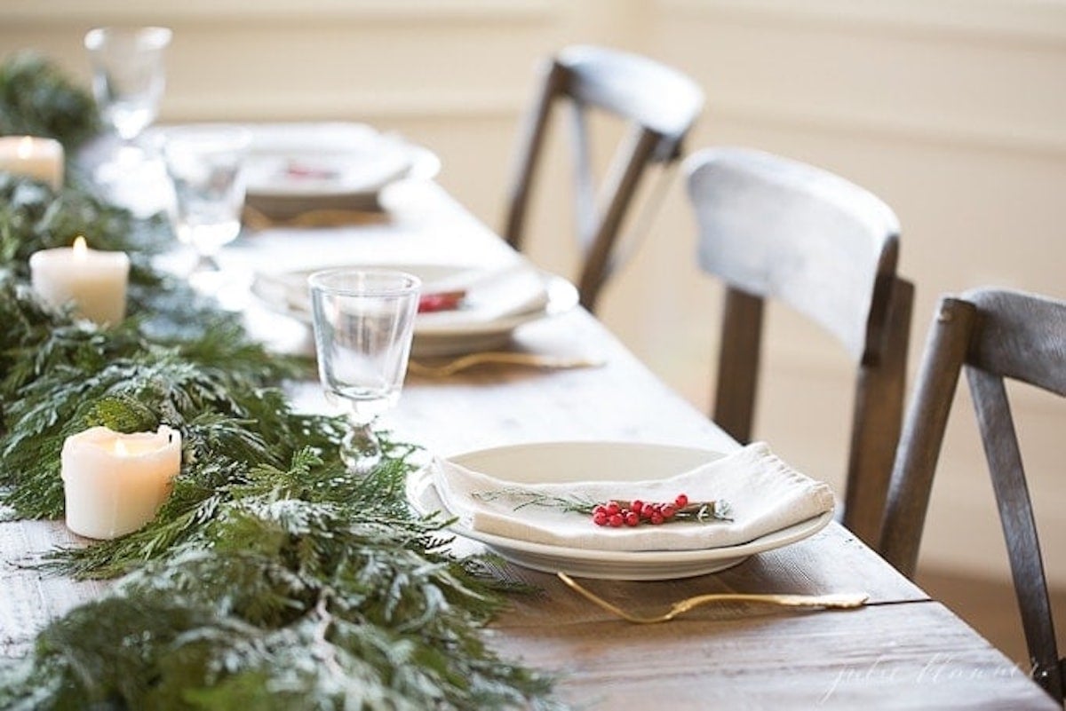 A Christmas table setting adorned with garland and candles.