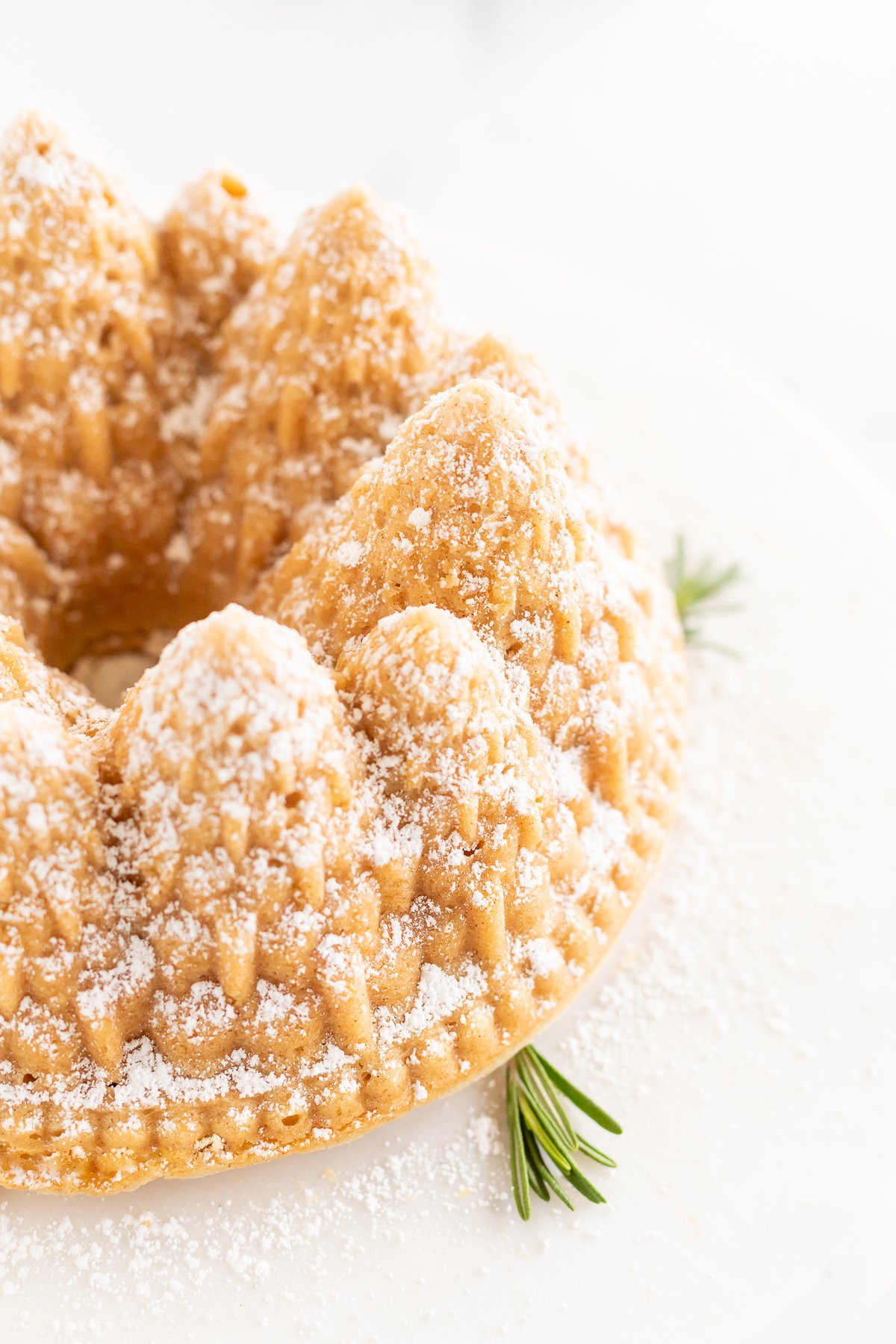 A cinnamon pound cake topped with powdered sugar and rosemary.