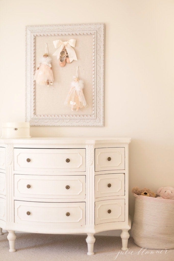 cream bedroom with pin board dresser and basket of stuffed animals