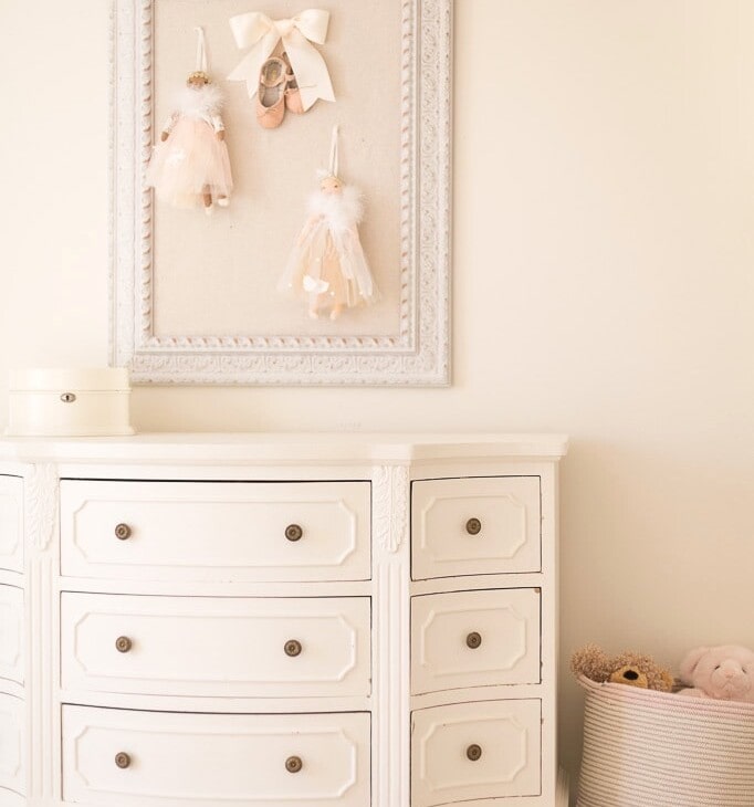 cream bedroom with pin board dresser and basket of stuffed animals